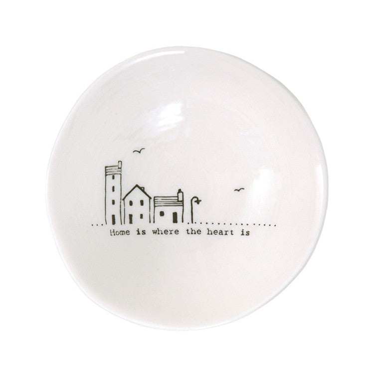 Home is where the heart is written on a white bowl with house illustration 